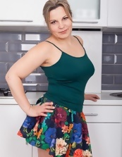 Chubby woman in nice colorful skirt strips in the kitchen